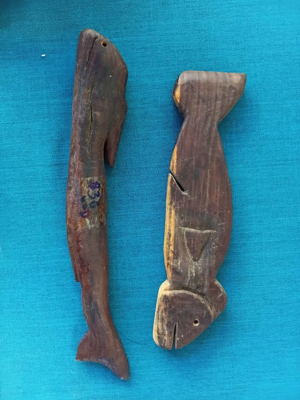 Two carved wooden fish on a blue cloth