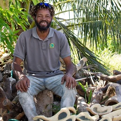 Glenmore McKenzie, seated among wood carvings