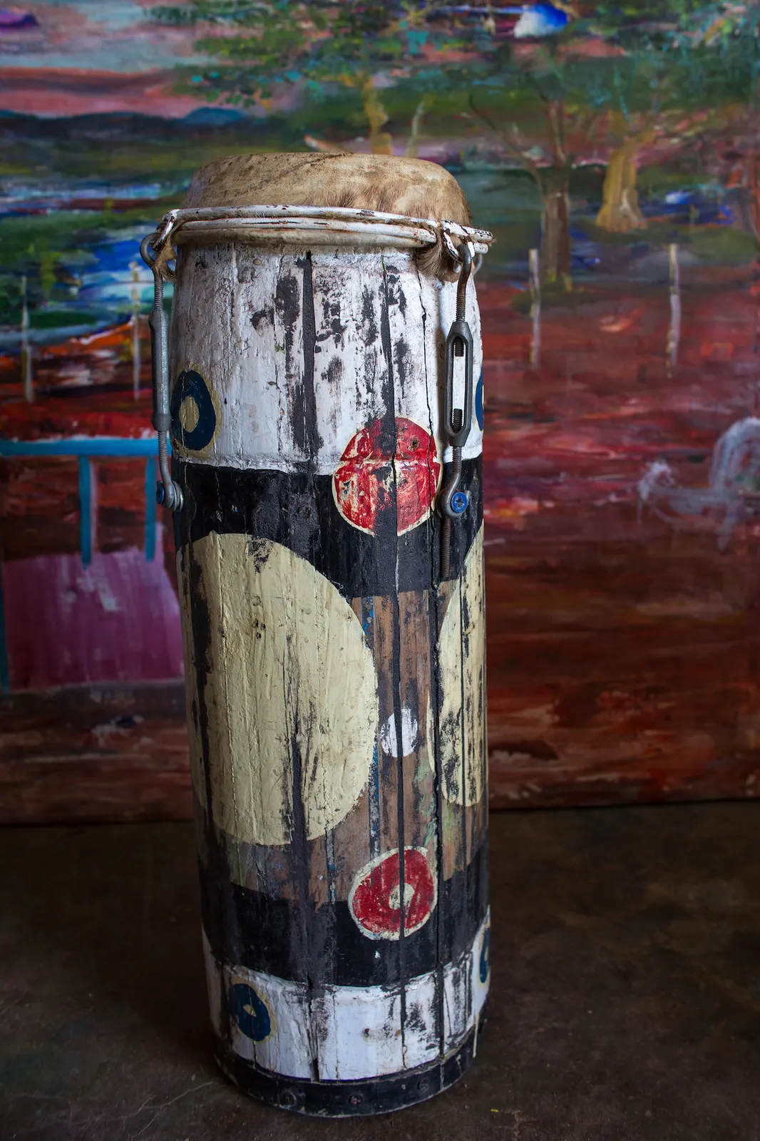 A tall hand drum painted white, black and cream with red and blue circles