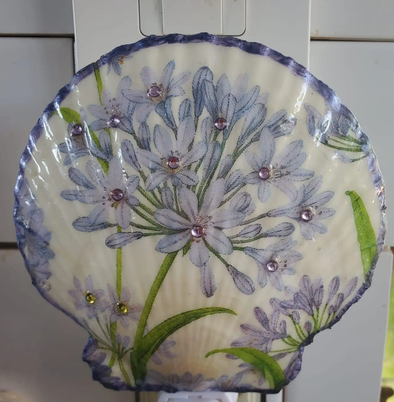 A scallop shell night light decorated with lilac agapanthus flowers and small gems