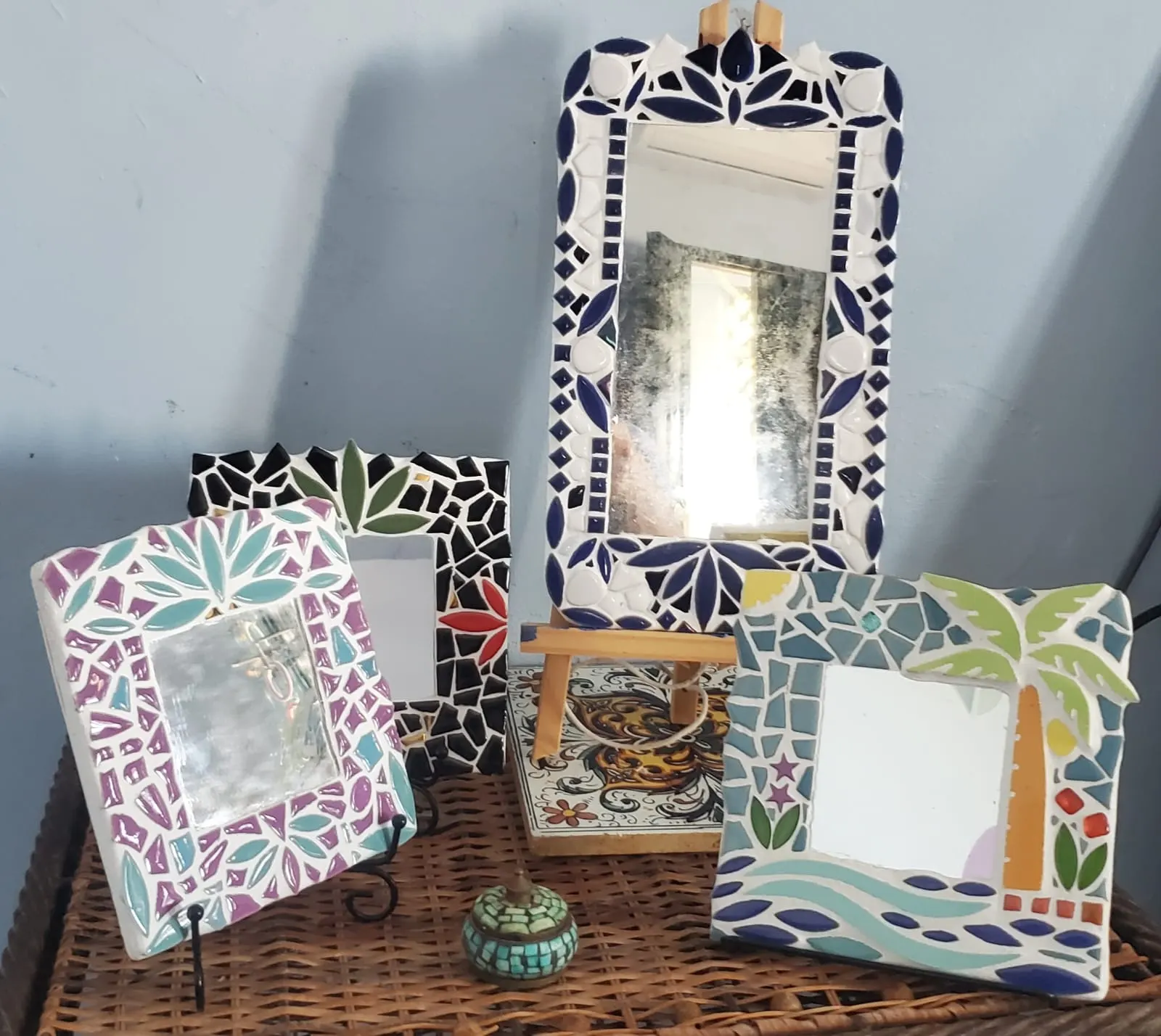 Four mirrors with mosaic frames, one with a palm tree and the sea