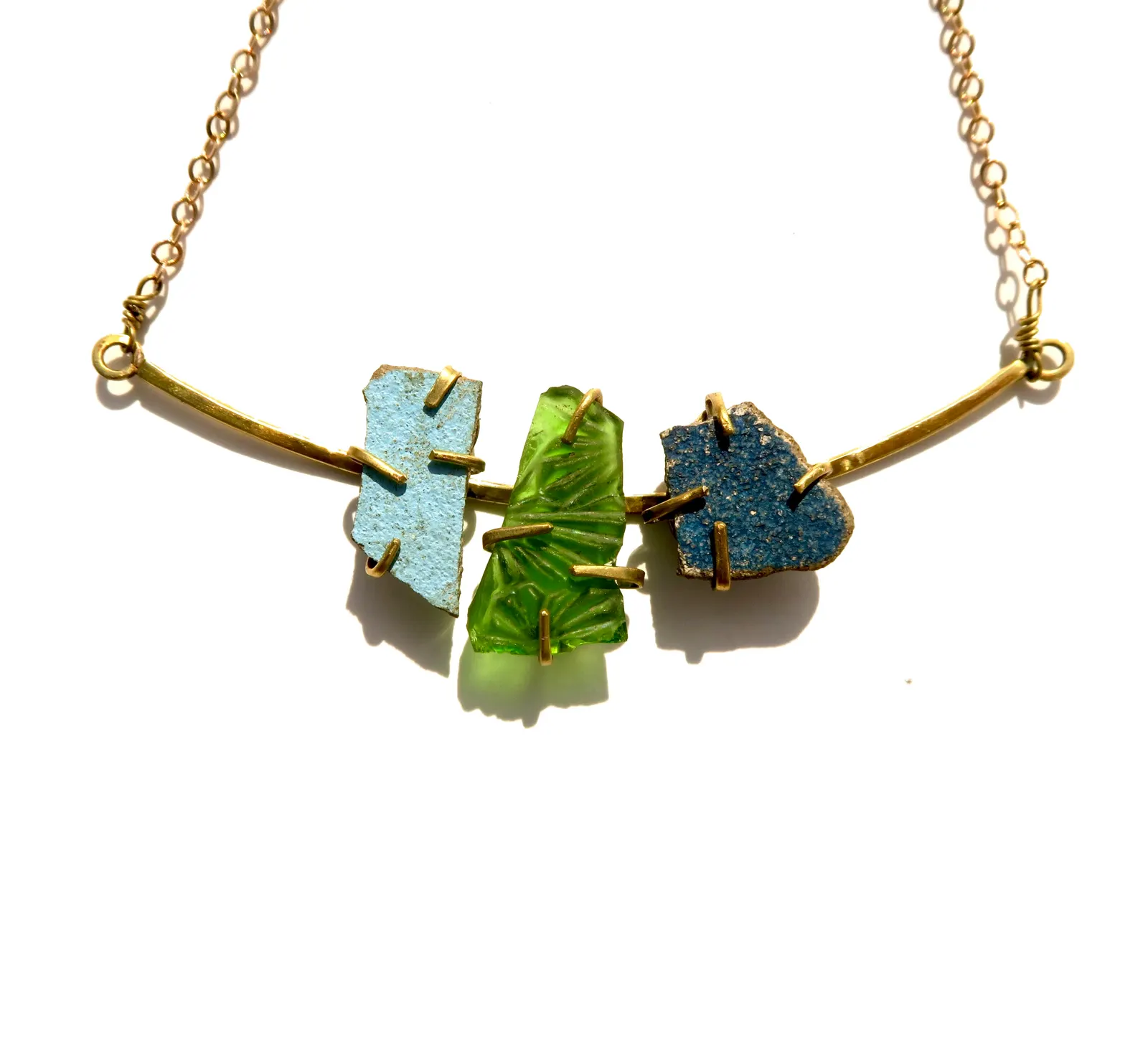 A necklace of three pieces of blue, green and turquoise glass and tile, set in brass on a chain