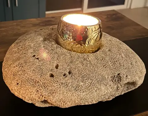 A candle in a gold holder set into a piece of beach rock