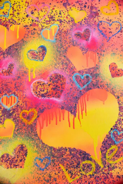 A painting of hearts in yellow, orange, pink and blue, sprayed, spattered and dripping, with “Love” written in the corner