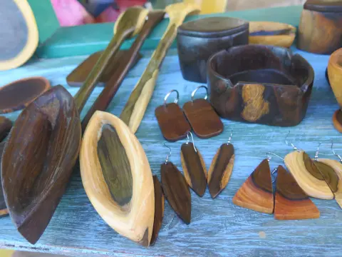 Carved wooden bowls, spoons, a lidded box and wooden earrings on a blue table