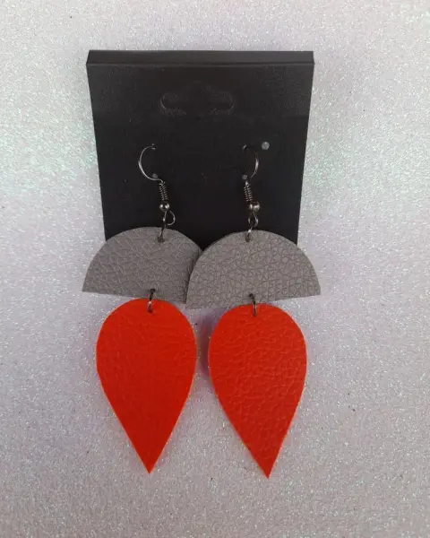 Faux leather earrings, a grey half-moon above an orange leaf, on a black card
