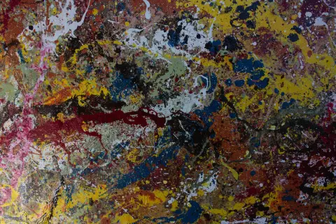 A drip painting in yellow, red, blue, white and brown