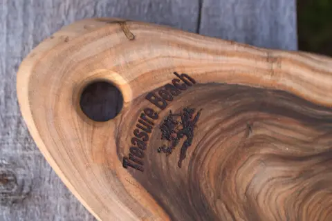 A wooden board with a hole for hanging, engraved “Treasure Beach”