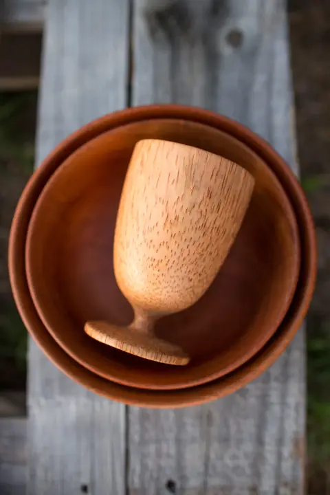 A turned wooden goblet resting in two wooden bowls