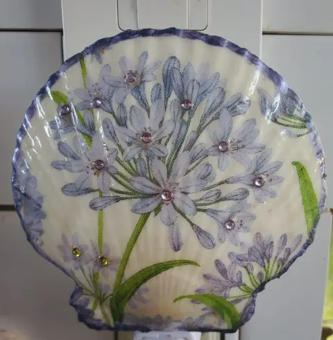 A scallop shell night light decorated with lilac agapanthus flowers and small gems