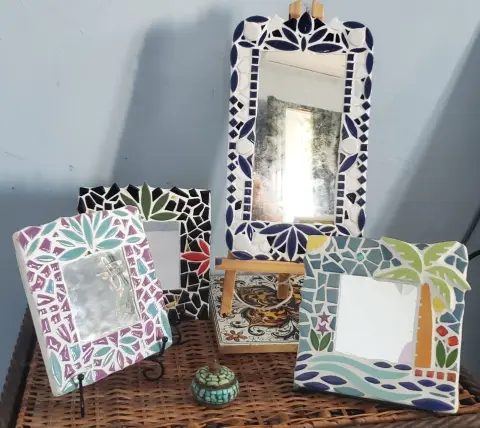 Four mirrors with mosaic frames, one with a palm tree and the sea