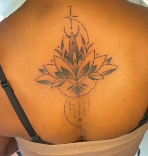 A lotus tattoo with a crescent moon and a star, on an upper back