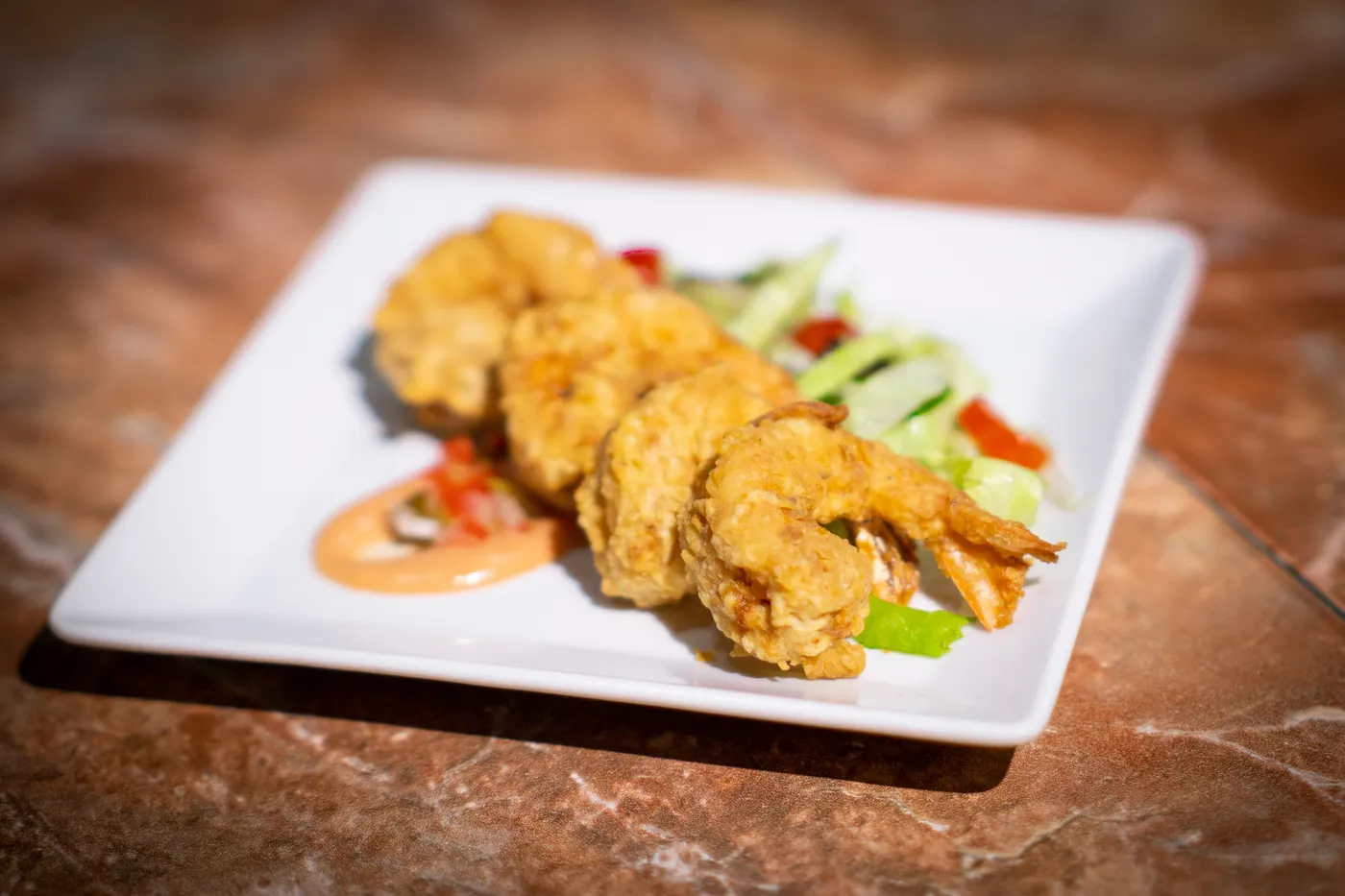 Beyond Sunset Bar and Smoke Grill — Fried shrimp on a white plate with a pink sauce and a small green salad