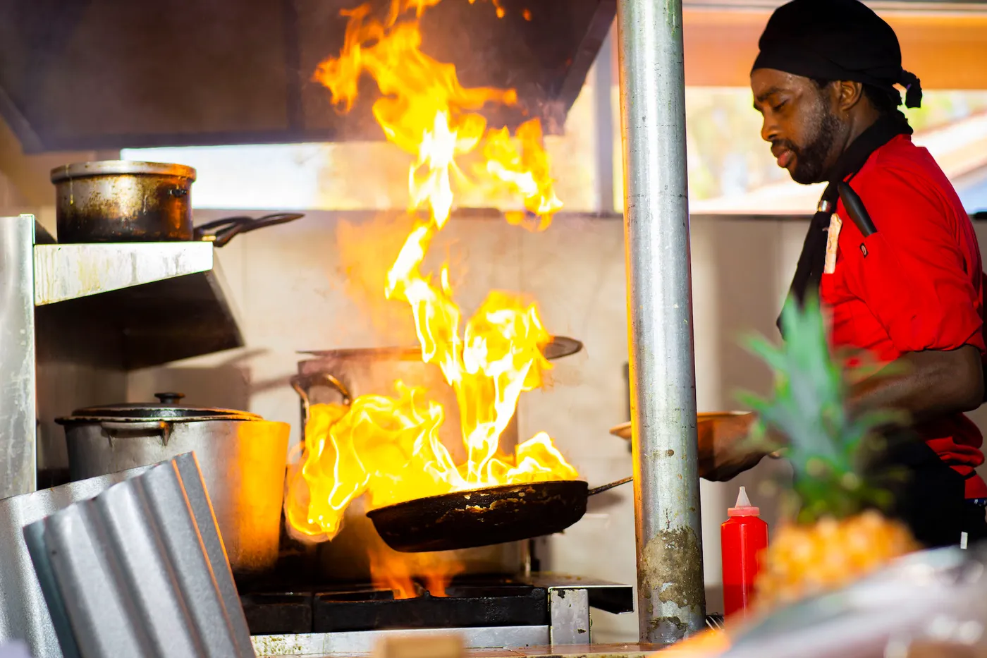 Beyond Sunset Bar and Smoke Grill — A cook in a red shirt in the open kitchen, with a flame rising from a pan