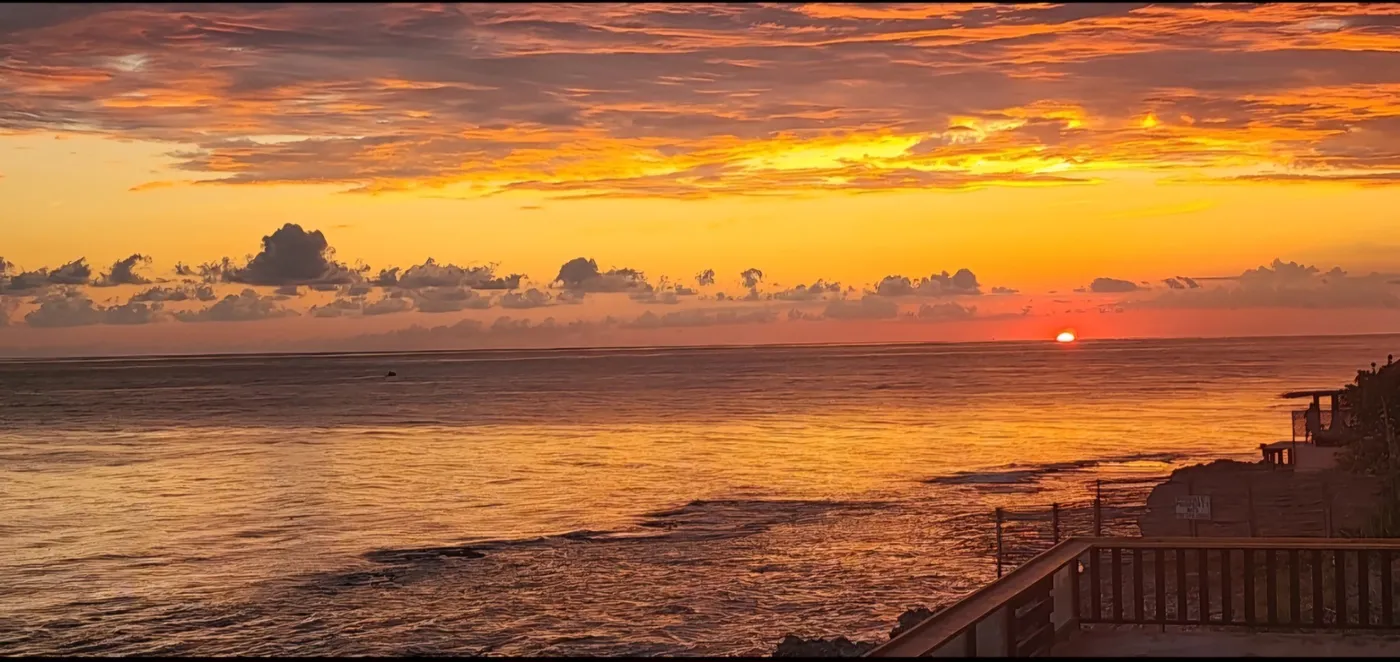 The sun setting over the Caribbean Sea in orange and gold, seen from the restaurant deck at Beyond Sunset