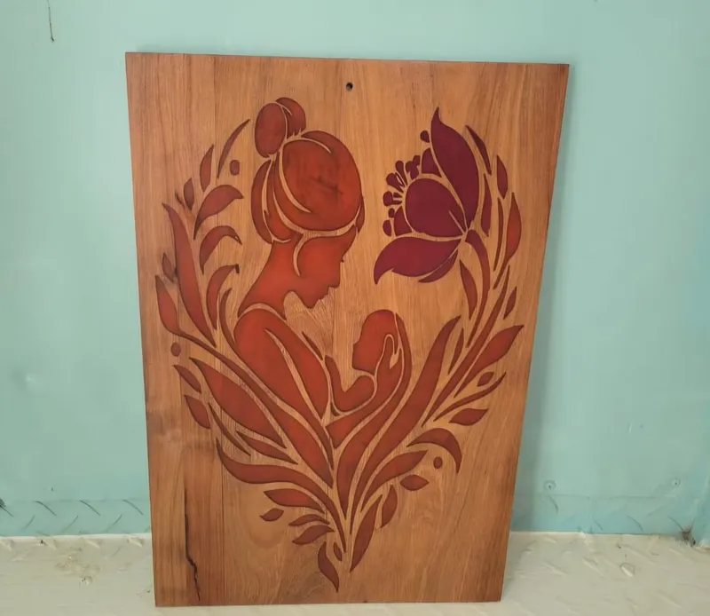 A wooden wall panel carved with a mother holding her child among leaves and a flower